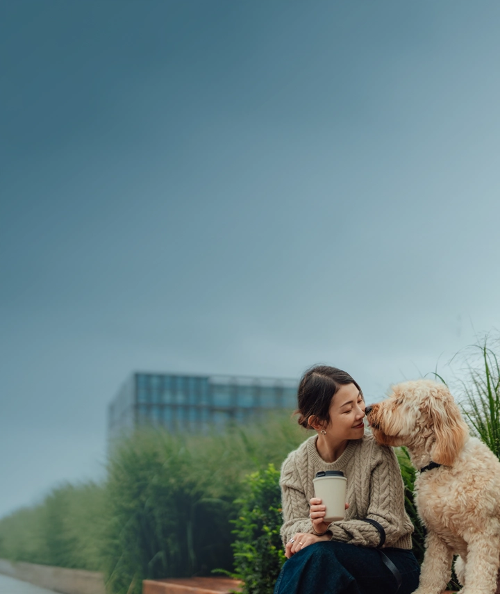 An Asian woman in her 30s leaning in to snuggle with her white fluffy dog