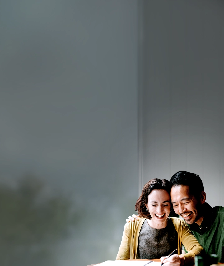 A woman and a man laughing while writing in a notebook