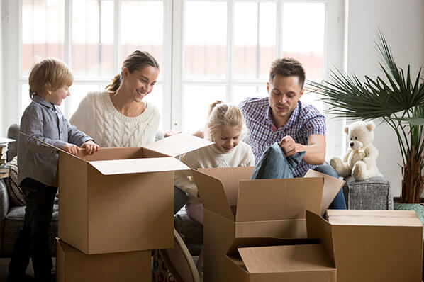 Mother, father, young boy and girl opening moving boxes in living room