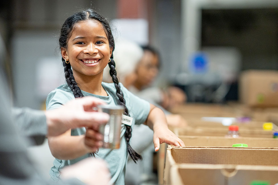 sweet mixed-race girl packing donations at a local food bank