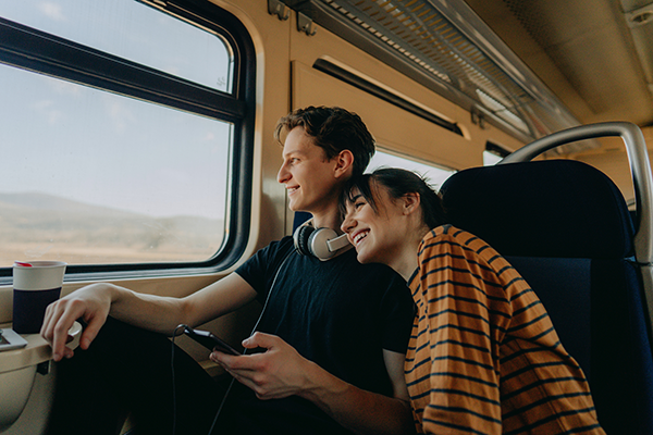 Two people on board a train, looking out the window excitedly.