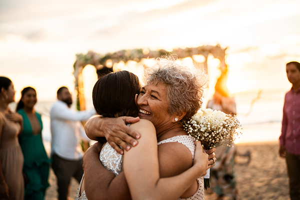 two women hugging at a wedding on the beach