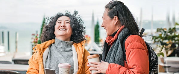 Two women laughing over coffee